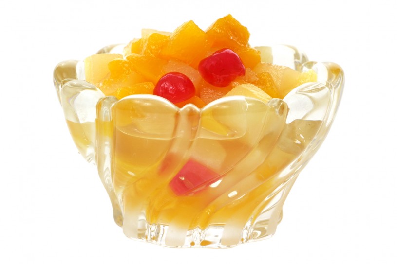 Glass dish filled with fruit cocktail on a white background.